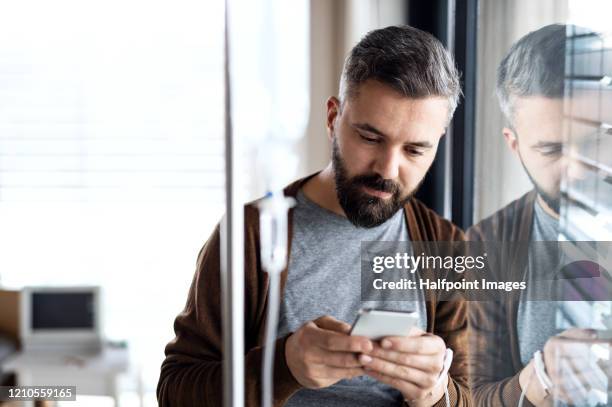 a sad and depressed man patient in hospital room, using smartphone. - frustrated on phone stock pictures, royalty-free photos & images