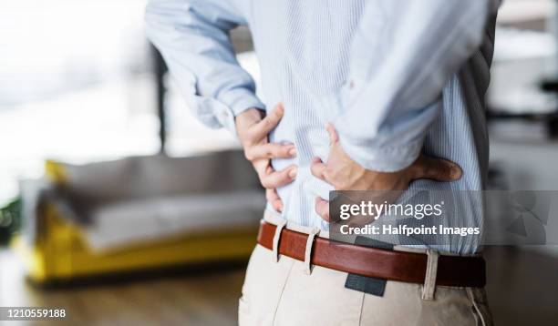 a midsection of businessman at home, feeling pain in back. - back pain man stock pictures, royalty-free photos & images