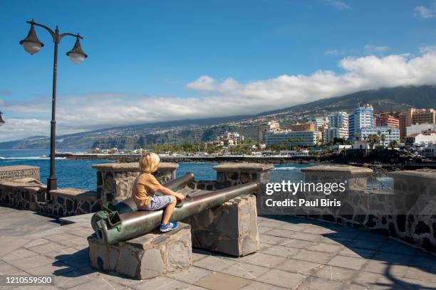 little boy on a old cannon in public castillo san felipe, a medieval fortress in puerto de la cruz, tenerife - puerto de la cruz tenerife stock pictures, royalty-free photos & images