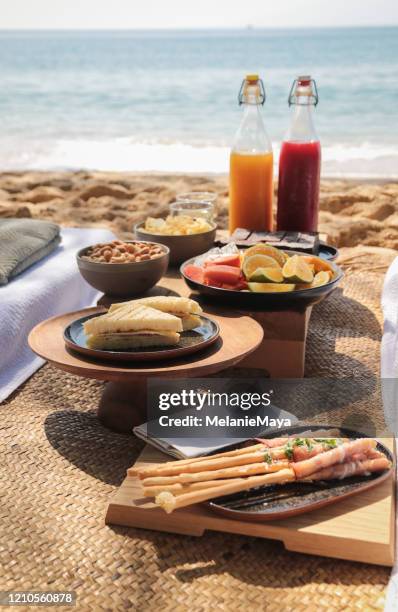 beach picnic by the sea with snacks and fruit and juice drinks - beach picnic stock pictures, royalty-free photos & images