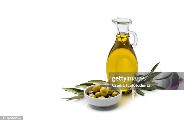olijfolie en olijven geïsoleerd op reflecterende witte achtergrond - olijfolie stockfoto's en -beelden