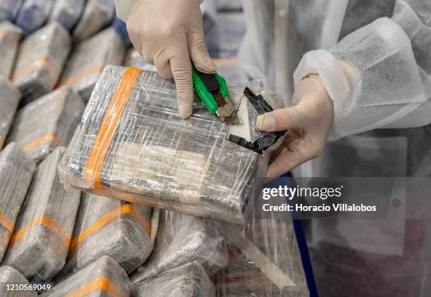 Police officer opens one of the 1 kg cocaine bricks shown during a press conference given by the Director of the Judicial Police National Unit to...