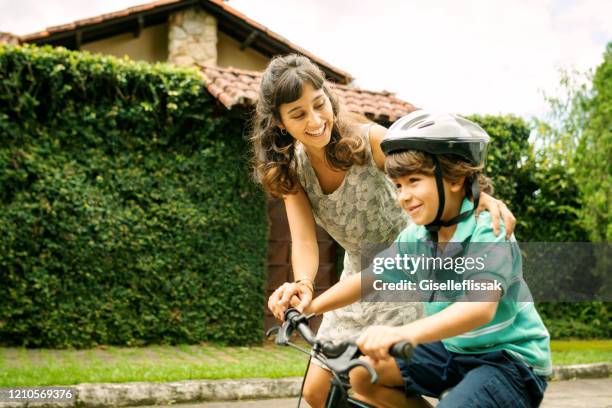 mother teaching son to ride a bike on the street - cycling class stock pictures, royalty-free photos & images