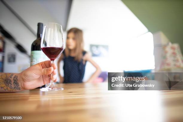 In this photo illustration a child looks at the parents pouring an alcoholic beverage, a red wine, on April 15, 2020 in Bonn, Germany.