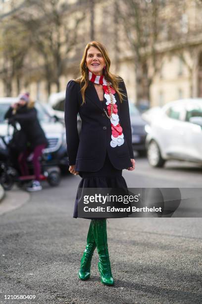 Anna Dello Russo wears a white and red striped scarf, a navy blue jacket with shoulder pads, a ruffled skirt, green leather high boots, outside Miu...