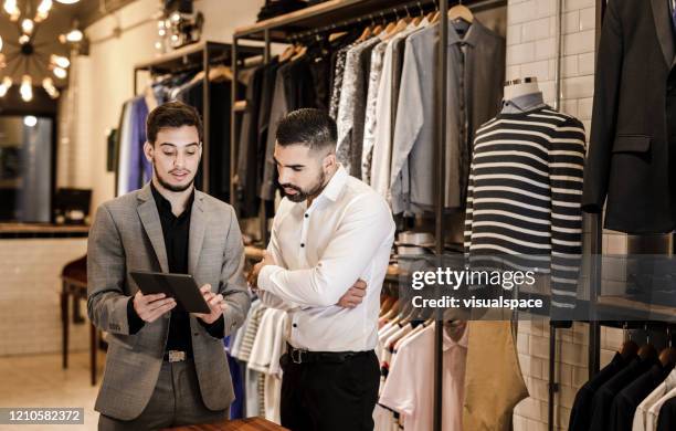 young man choosing a suit style from a digital tablet - shop assistant stock pictures, royalty-free photos & images