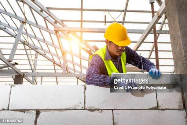bricklayer builder working with autoclaved aerated concrete blocks. walling, installing bricks on construction site, engineering and constructions concepts. - masonry stock pictures, royalty-free photos & images