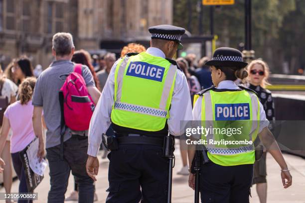 de mannelijke en vrouwelijke aziatische metropolitaanse politieambtenaren patrouilleren de menigten toeristen buiten de slangen van het parlement in westminster, londen, het uk - metropolitan police van londen stockfoto's en -beelden