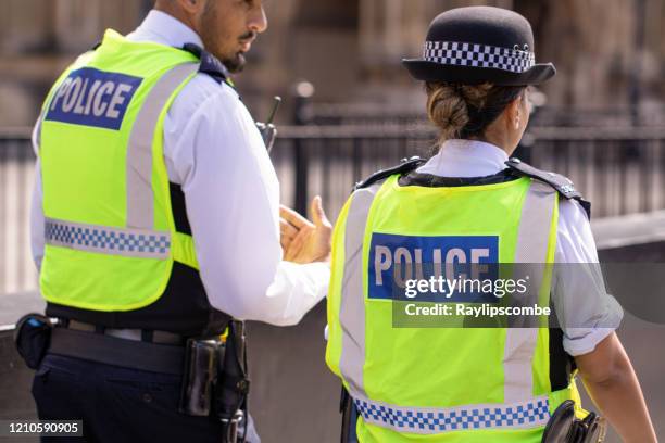 agenti di polizia metropolitana asiatici di sesso maschile e femminile pattugliano la folla di turisti fuori dagli hoses of parliament a westminster, londra, regno unito - uniforme della polizia foto e immagini stock