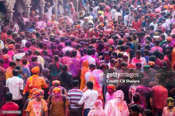 large crowds of hindu devotees celebrating holi in temple at nandgaon - powder throw fotografías e imágenes de stock