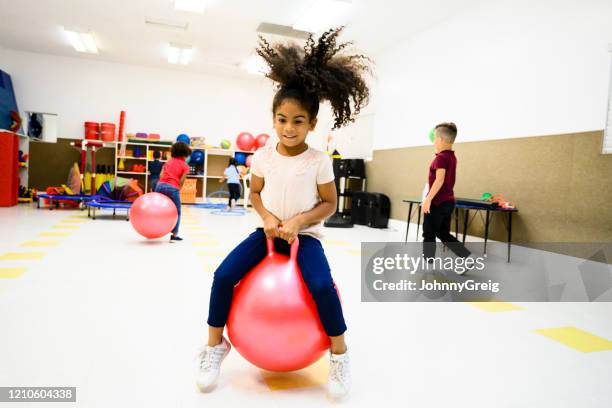 independent hispanic schoolgirl bouncing on fitness ball - saltar para cima e para baixo imagens e fotografias de stock