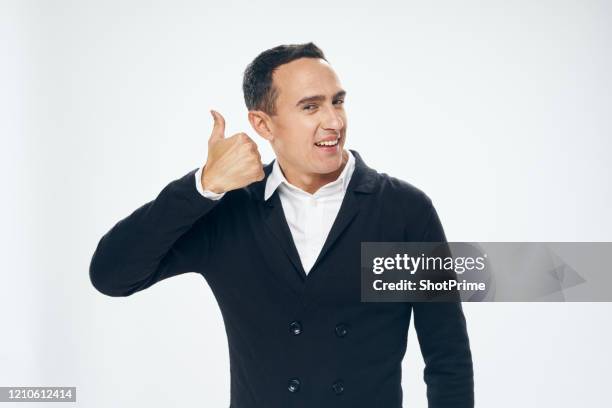 a man in a white shirt and black cloak smiles happily and shows a thumbs up, a young businessman, millionaire, celebrity, gray background, classic suit - black thumbs up white background stock pictures, royalty-free photos & images