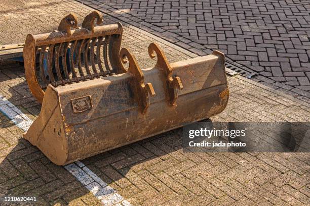 rusty bucket parts of a earth mover lying on the street - excavator bucket stock pictures, royalty-free photos & images