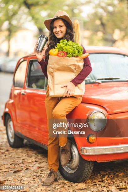 woman drinking coffee and holding groceries paper bag - coffee car design stock pictures, royalty-free photos & images