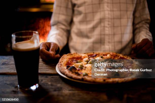 man eating pizza and drinking beer at a pub - artisanal food and drink uk imagens e fotografias de stock