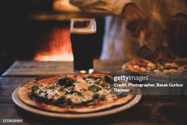 man eating pizza and drinking beer at a pub - artisanal food and drink uk imagens e fotografias de stock