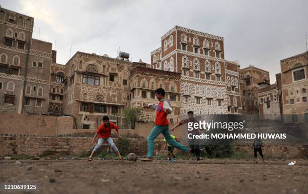 Picture taken on April 21, 2020 shows children playing football near old buildings in the historical quarter of the Yemeni capital Sanaa, which is...