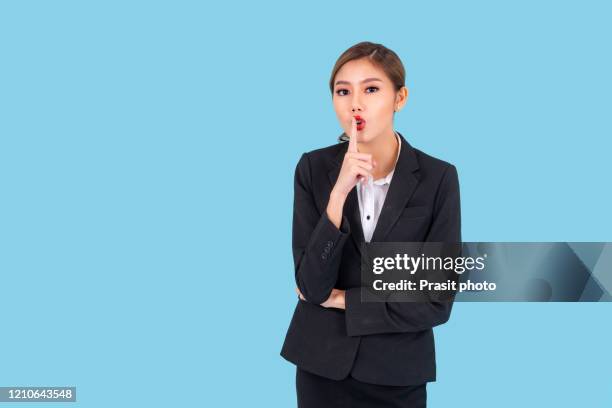 entrepreneur pretty young asian woman ,business woman secret hush pose portrait. young beautiful girl pose with arms crossed. isolated over cyan background. half body shot. - woman with finger on lips stock pictures, royalty-free photos & images