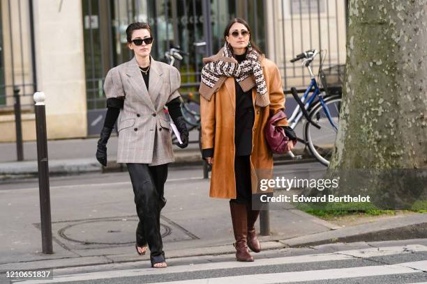 Sylvia Haghjoo wears sunglasses, a gray checked oversized blazer jacket with shoulder pads, black gloves, black flared pants, shoes, a necklace ;...