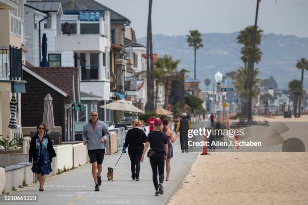 People exercise along the boardwalk near the Newport Beach pier amid Coronavirus social distancing regulations in Newport Beach, Calif., on March 31,...