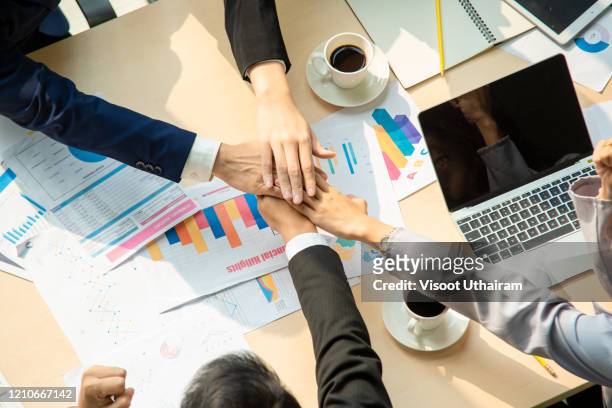 top view of business  people holding hands on top of one another in a symbol of unity while working in the creative office. - organisation chart stock-fotos und bilder
