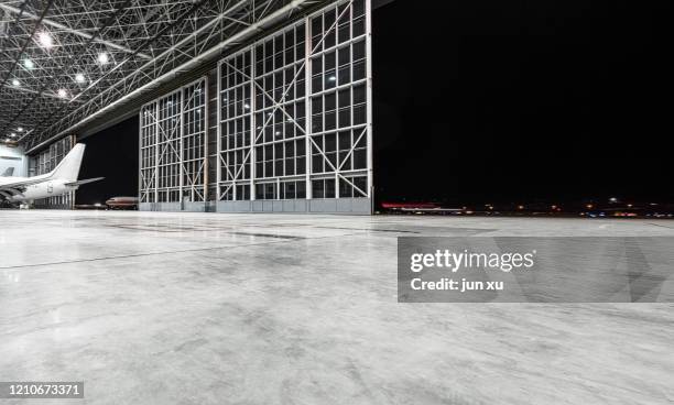 an empty, bright modern aircraft hangar - dark warehouse stock pictures, royalty-free photos & images