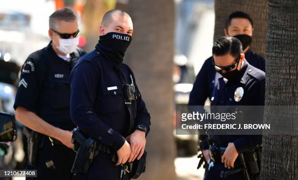 Los Angeles Police Department officers wear facial covering while monitoring an "Open California" rally in downtown Los Angeles, on April 22, 2020. -...