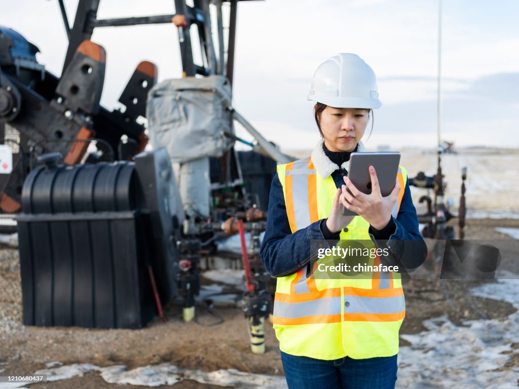 Asiatische weibliche Ölarbeiterin mit Tablet-PC