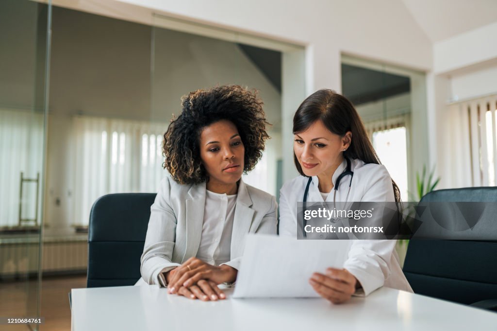 General practitioner showing test results to a charming mixed race woman.