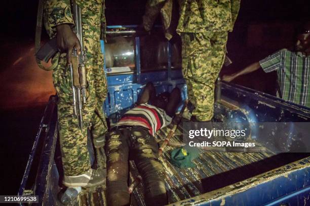 Soldiers stand over a man they found outside during curfew hours amid coronavirus crisis in Gulu. Uganda's coronavirus-related curfew was brought in...