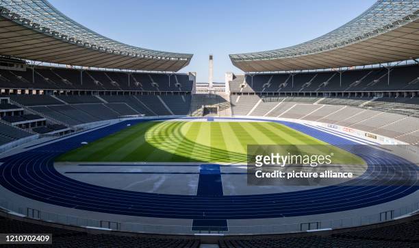 April 2020, Berlin: A view over the Olympiastadion Berlin shows empty tiers and deserted lawns in bright sunshine. Due to measures to contain the...