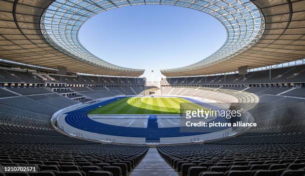 Dpatop - 23 April 2020, Berlin: A view over the Olympiastadion Berlin shows empty tiers and deserted lawns in bright sunshine. Due to measures to...