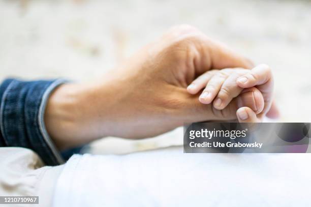 In this photo illustration a mother´s hand holds the hand of her baby on April 21, 2020 in Bonn, Germany.