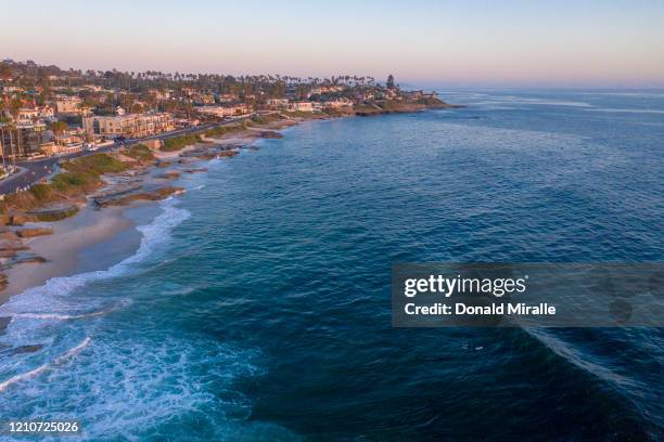 Coronovirus Photo Essay: Scenic view of a lone surfer at Windansea beach at sunset as large parts of the nation shut down schools and workplaces to...