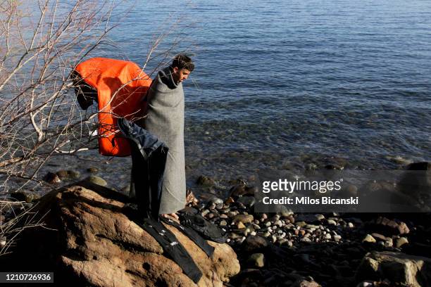 Asylum seekers who arrived from Turkey to the Greek island of Lesbos on March 5, collects his belongings from the sea near Skala Sykamnias, Lesvos,...