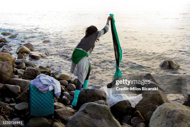 Asylum seekers who arrived from Turkey to the Greek island of Lesbos on March 5, collect his belonging from the sea near Skala Sykamnias, Lesvos, on...