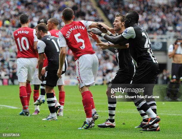 Thomas Vermaelen of Arsenal is pushed by Yohan Cabaye and Cheik Tiote of Newcastle after Gervinho is sent off during the Barclays Premier League...