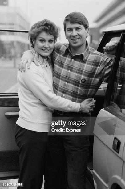 British newsreader and television presenter Angela Rippon hugging her husband, Christopher Dare, as they stand beside the open door of a car, 2nd...