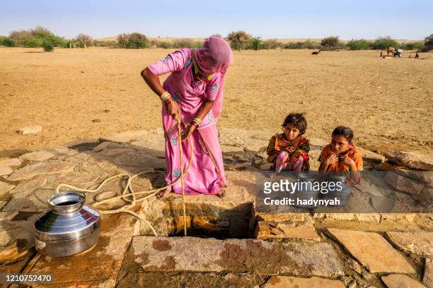 indian woman drawing water from the well, desert, rajasthan - rajasthani women stock pictures, royalty-free photos & images