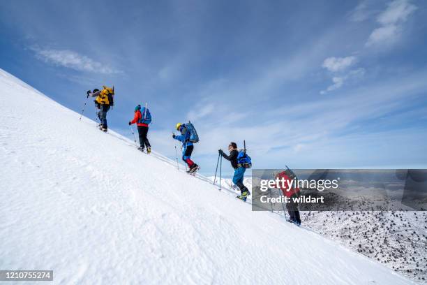 alpine mountain climbing team is walking to the summit of the high altitude mountain in winter - climbing mountain stock pictures, royalty-free photos & images