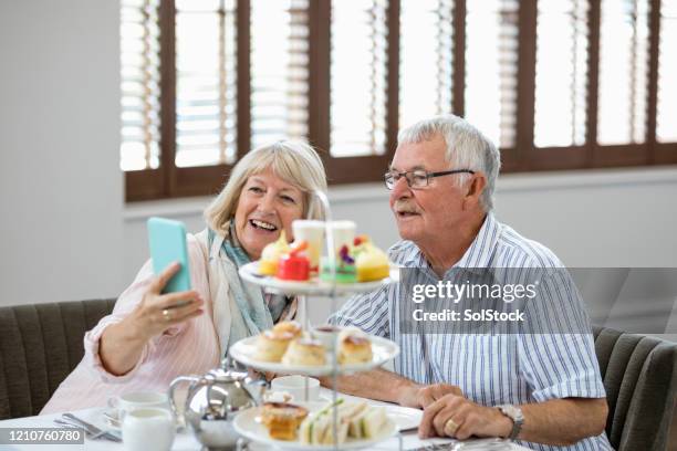senior couple taking selfie on smartphone at afternoon tea - cakestand stock pictures, royalty-free photos & images