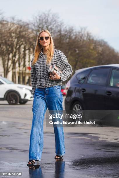 Charlotte Groeneveld wears sunglasses, a black and white checked tweed jacket, blue denim flared jeans, shoes, outside Chanel, during Paris Fashion...