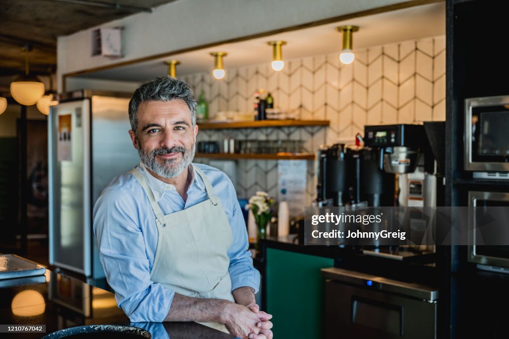 Barista macho sonriente listo para preparar la bebida en la cafetería