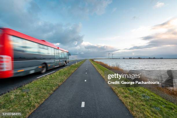 bus moving fast on the road next to the water - bus lane stockfoto's en -beelden