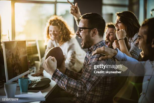 cheerful programmers cheering while watching their sports team on pc in the office. - game developer stock pictures, royalty-free photos & images