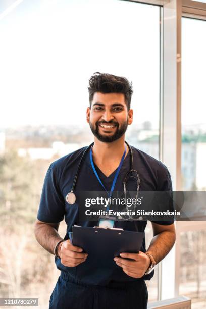 portrait of male indian doctor wearing a blue coat. - india lab stockfoto's en -beelden