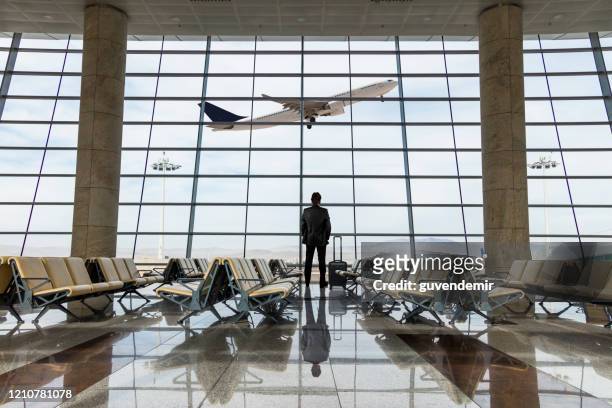 uomo d'affari con bagagli in attesa in aeroporto - aeroporto foto e immagini stock
