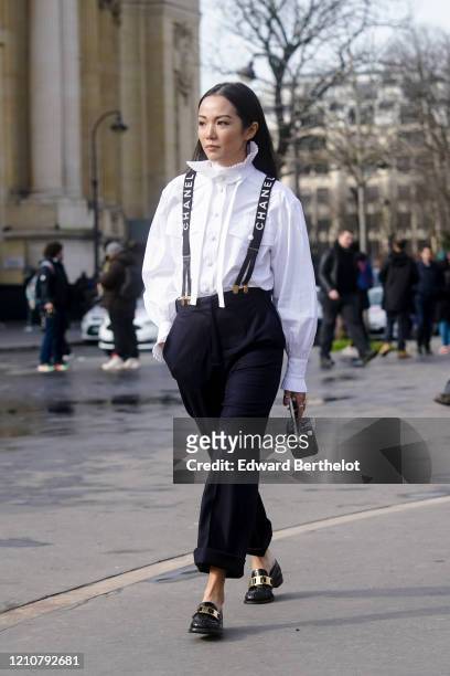 Yoyo Cao wears a white shirt, Chanel straps, navy blue pants, black leather shoes, a quilted mini Chanel bag, outside Chanel, during Paris Fashion...