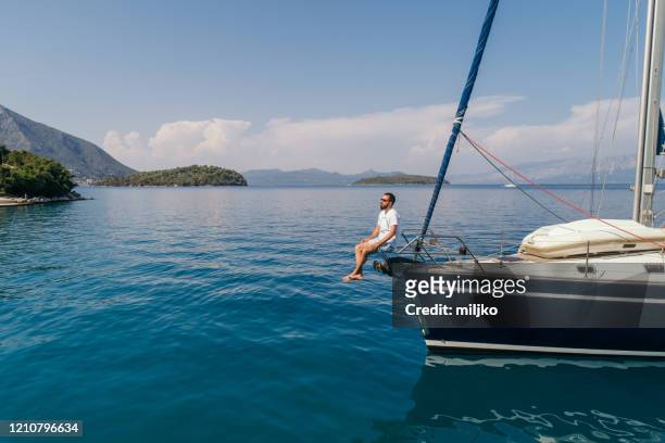 homme appréciant la voile sur l’arc de bateau à voile - sailing greece photos et images de collection