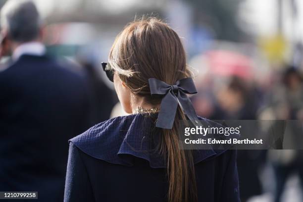 Guest wears a bow tie on the hair, a ruffled blue dress, a golden necklace, outside Chanel, during Paris Fashion Week - Womenswear Fall/Winter...
